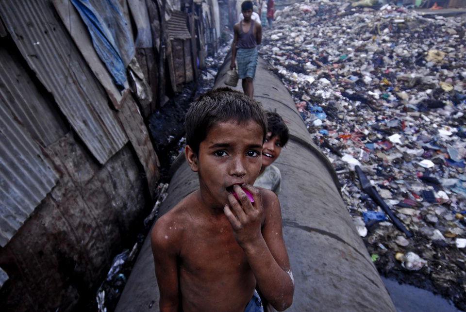 A boy stood at one of the big water pipes running across the Dharavi slum, photo: Lecercle/ Creative commons