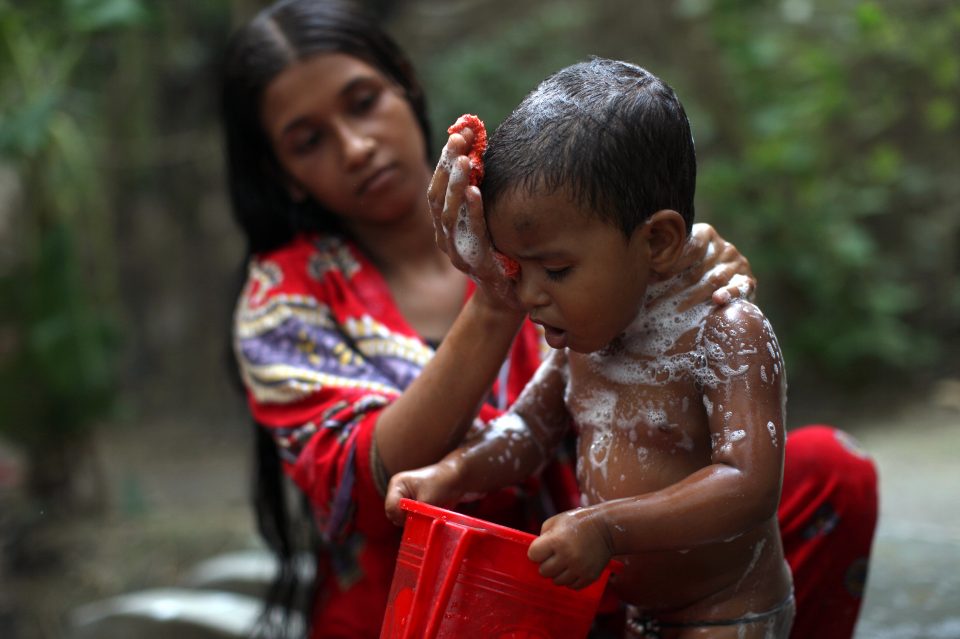 Tohomina Akter, 18, bathes her daughter Adia, 17 months, at the neighborhood well in Char Baria village, Barisal, Bangladesh, on Thursday, April 19, 2012. This picture is from the series "A day with Tohomina Akter." Tohomina, 18, lives with her husband Alamin, 24, and daughter Adia, 17-months-old. Tohomina participates in a maternal and infant nutrition program called Nobo Jibon run in part by Hellen Keller International. The program stresses proper nutrition in a child's 1,000 days from pregnancy to age two, with an emphasis on breastfeeding and cultivating nutritious vegetables in home gardens. The goal is to encourage social and behavior change and prevent stunting in children. Nobo Jibon is what the SPRING (Strengthening Partnerships, Results, and Innovation in Nutrition Globally) program will look like when it is launched in Bangladesh later in 2012. SPRING is a new USAID-funded nutrition improvement effort. Tohomina grows amarinth, spinach, peppers and other vegetables in her small garden. She spends most of the morning and early afternoon cooking these vegetables plus rice for her family's meals, as well as cleaning the house and looking after her daughter. Tohomina married Alamin when she was 15. She caught her husband's eye when she was walking to school and he saw her as he was laboring on a road. He told his parents he wanted to marry her, his parents talked to her parents and the marriage was arranged. Tohomina finished grade 7. She hopes she can help educate her daughter to be a doctor. Photo by Laura Elizabeth Pohl